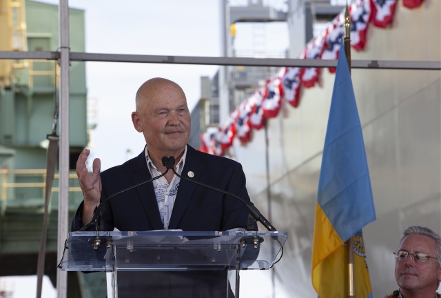 Rear Admiral Mark H. Busby standing at podium at at DKI christening