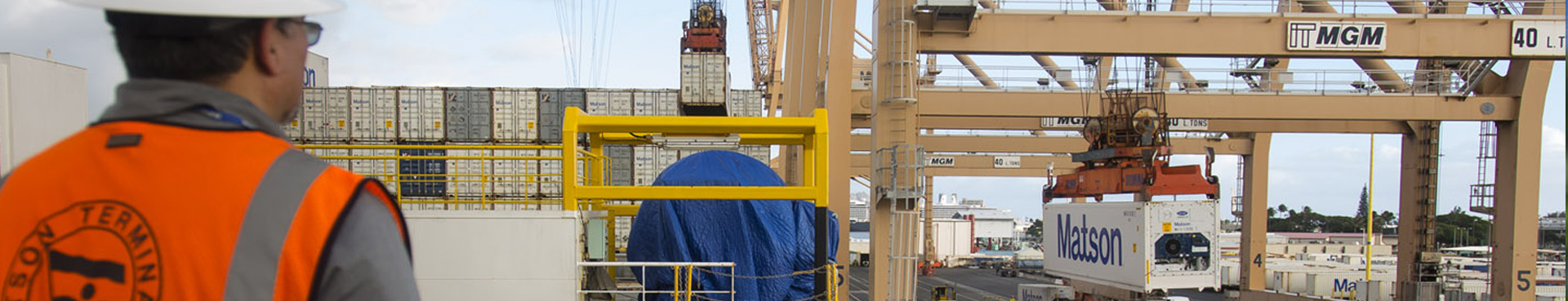A terminal worker looks on as a containers is lifted to the ship.