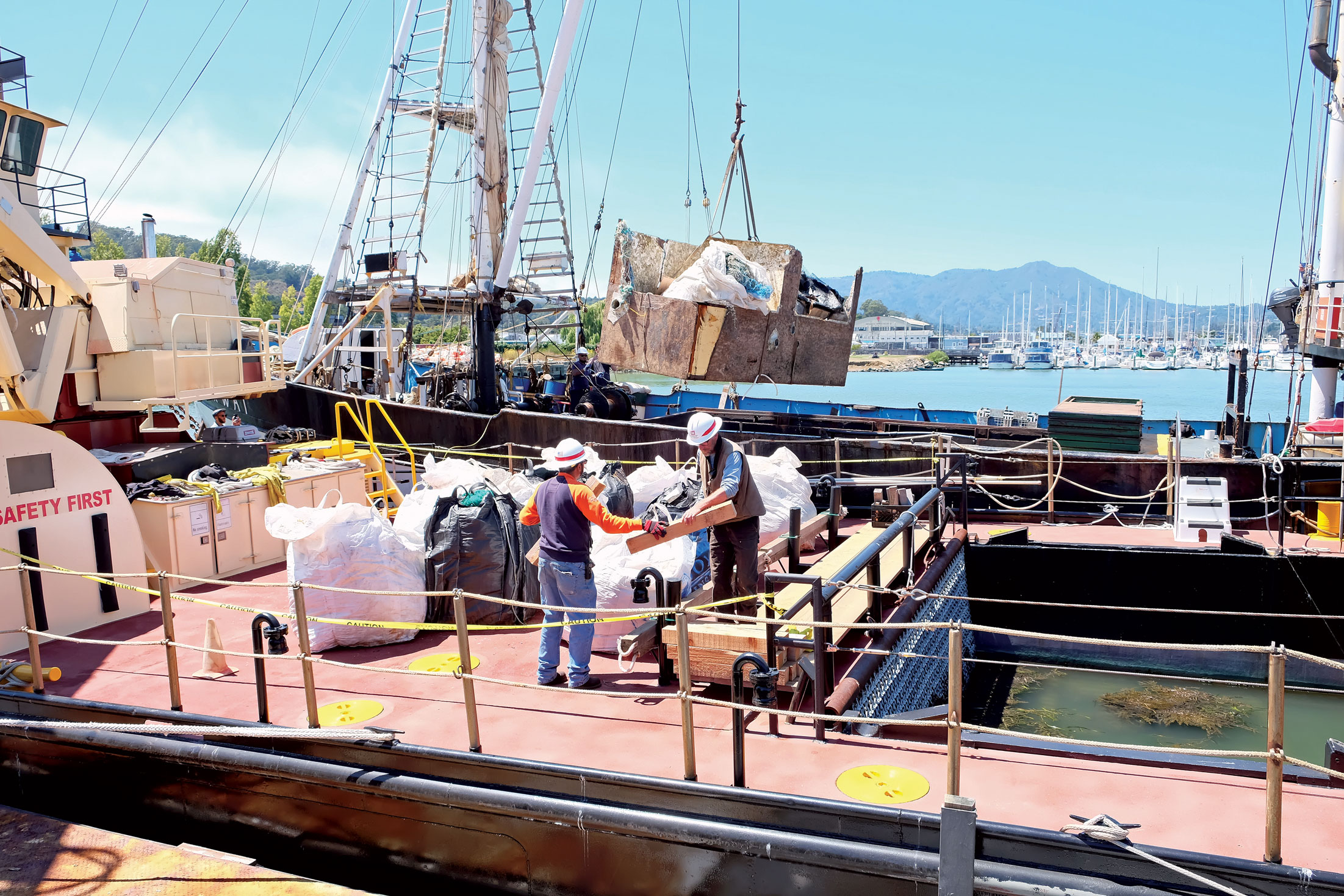 A crane lifts loads of trash from the Kwai deck.