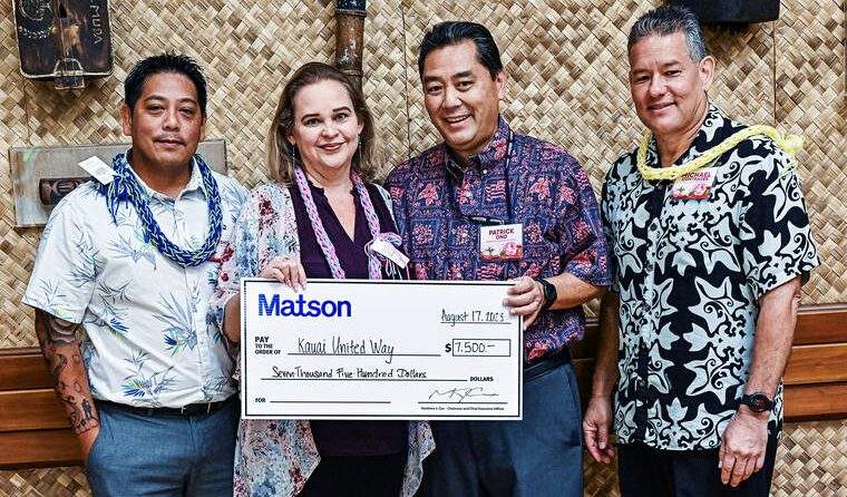 United Way and Matson staff wear leis and stand with presentation check.